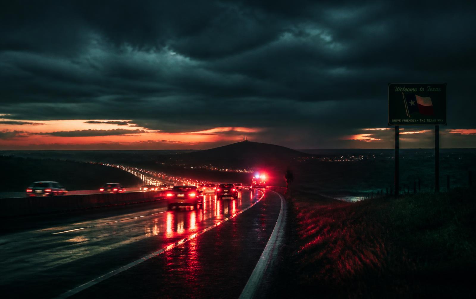 Texas highway at dusk after a storm, with traffic lights reflecting on wet asphalt